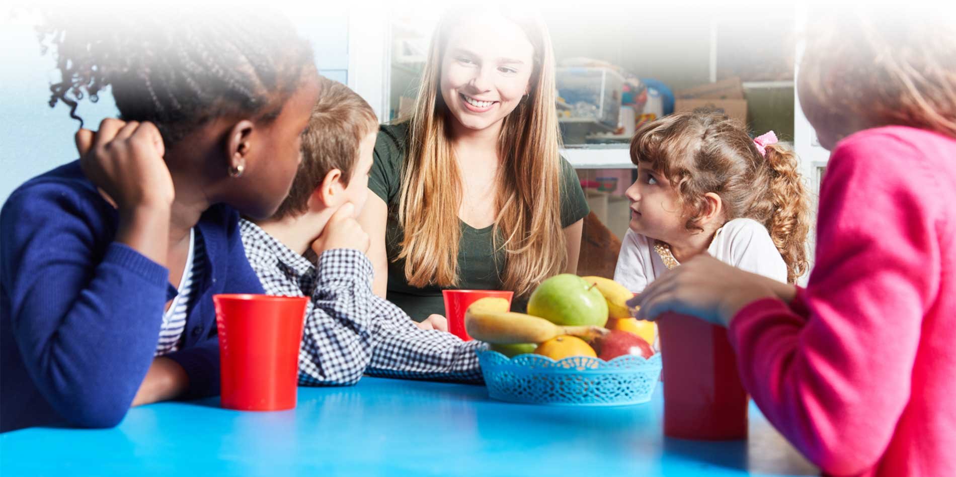 A group of kids listening to their tutor while eating apples.