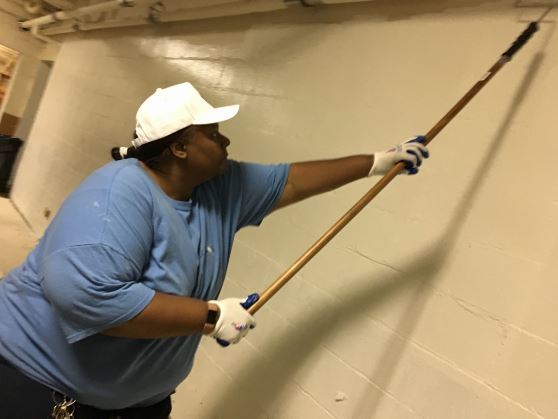 Resident learning to use paint roller on walls