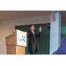 Woman standing next to a podium using expressive hand gestures while speaking to the audience