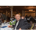 A man smiling at the table holding raffle tickets